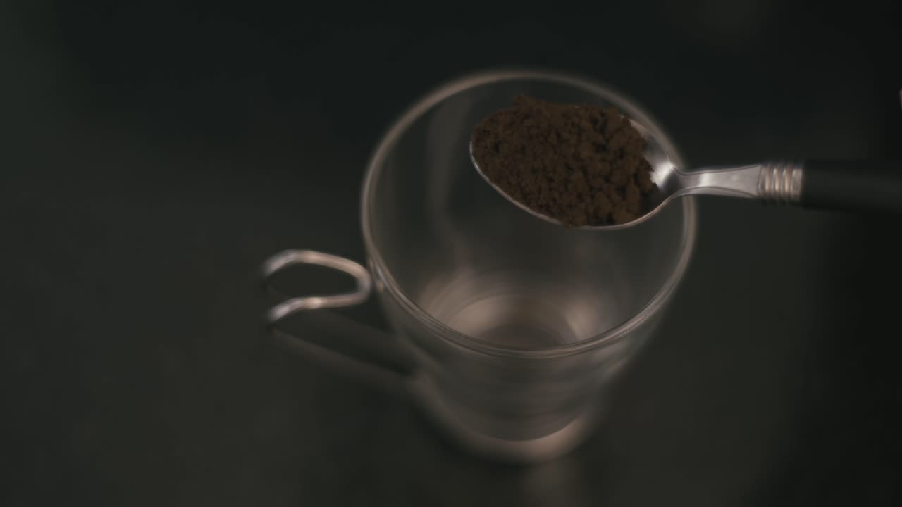 spoon with ground coffee placed in a cup, creating a focus and blur effect while highlighting its consistency
