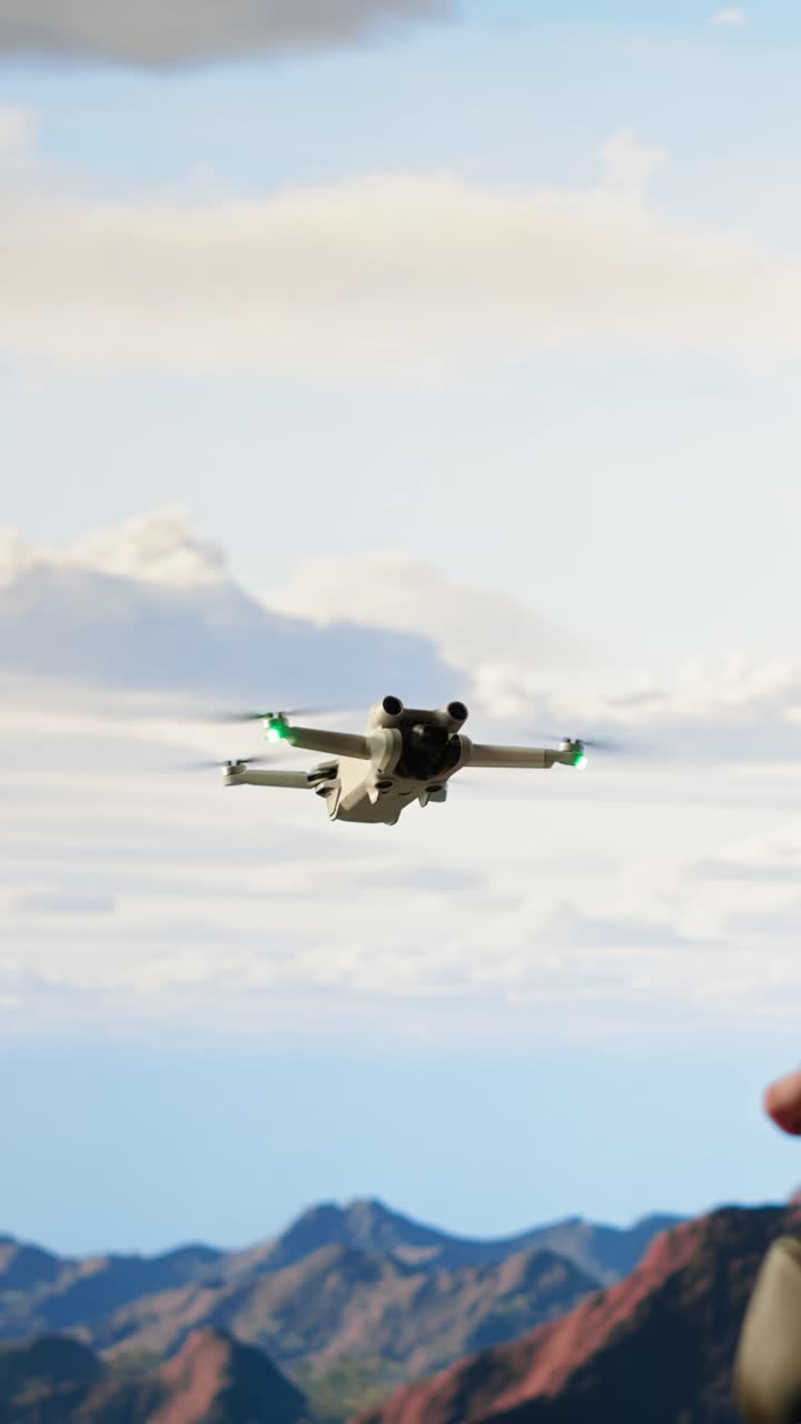 Modern Drone Hovering in Sky with Mountains and Pilot's Hands