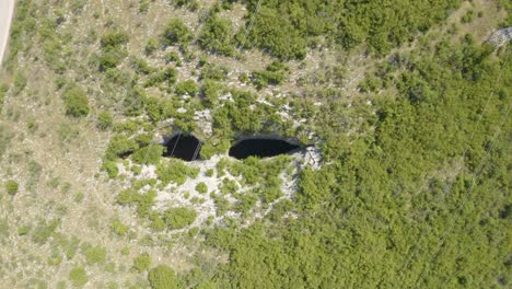 Vista-Aérea-De-Los-Ojos-De-Dios-En-La-Cueva-De-Prohodna,-Dos-Agujeros-Con-Forma-De-Ojo-En-Karlukovo,-Bulgaria