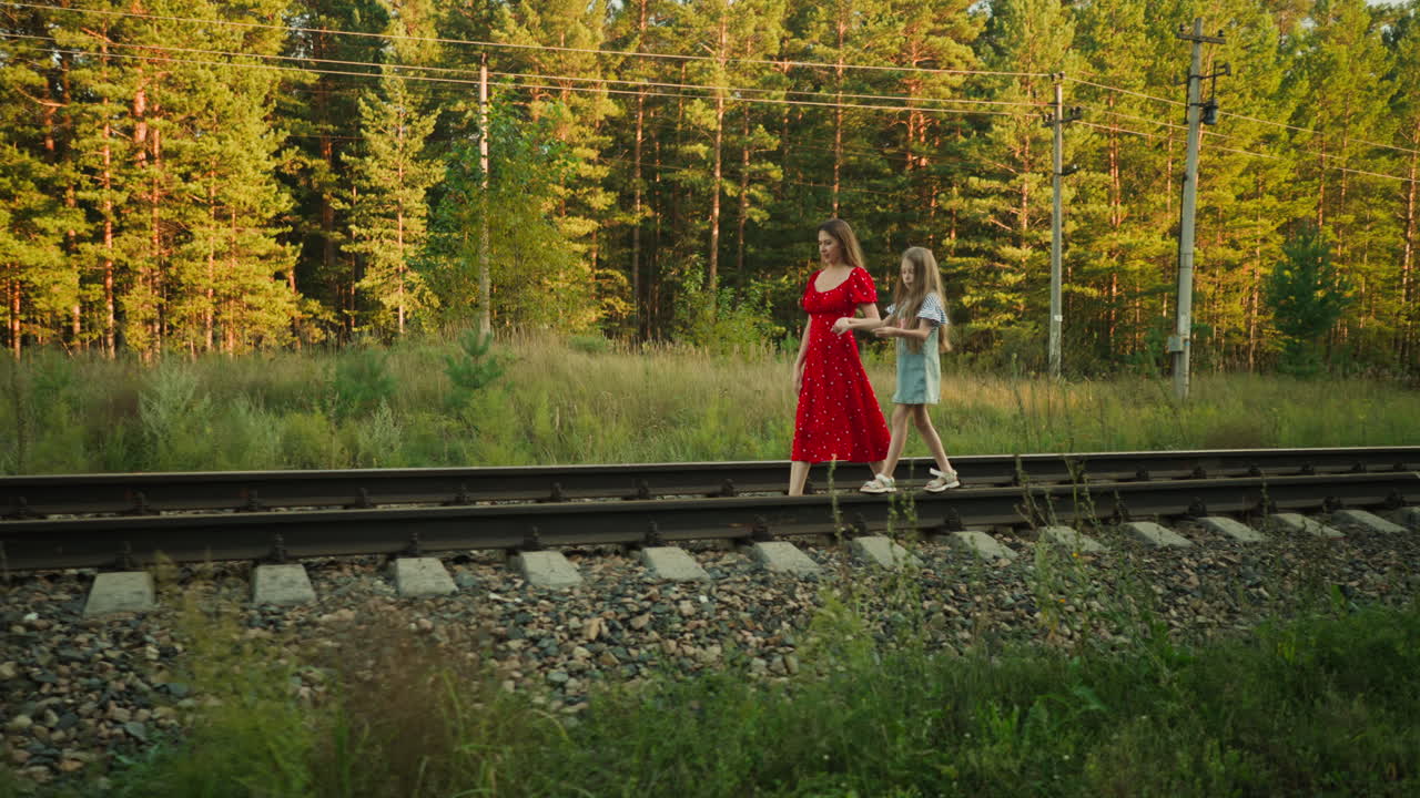 kid walking carefully on rail beam holding sister hand for support as they move together through rural countryside with sunlight casting soft glow on surrounding greenery