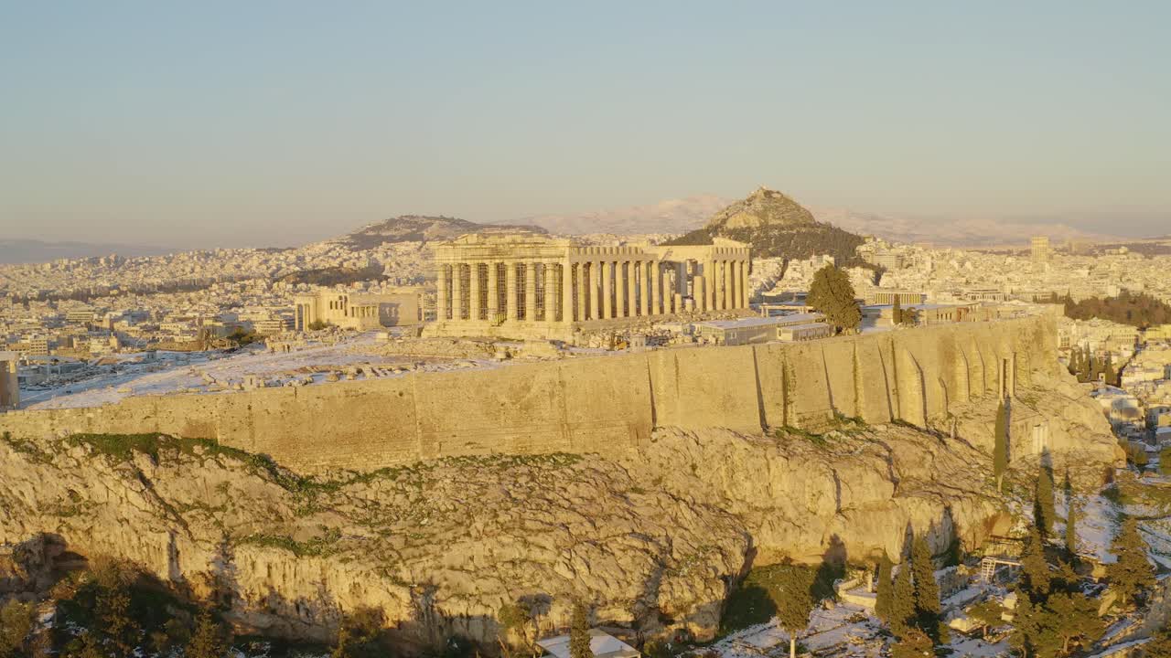 vista aérea sobre la colina de la acrópolis, que revela el paisaje nevado de atenas, hora dorada en grecia - aumento, disparo de drones
