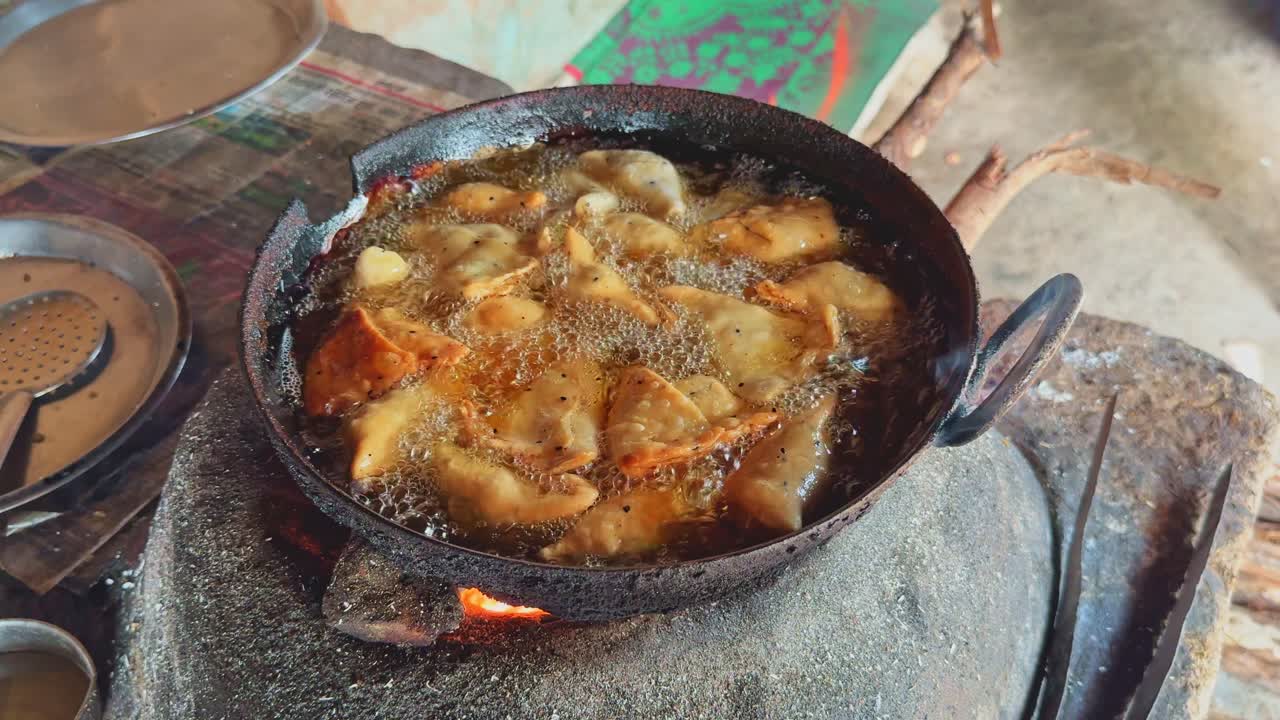 Golden samosas frying in bubbling oil on a traditional clay stove, creating a rustic Indian street food scene with rich aroma and sizzling texture