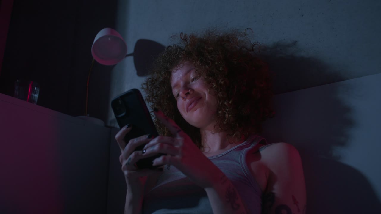 mujer usando el teléfono en el dormitorio por la noche