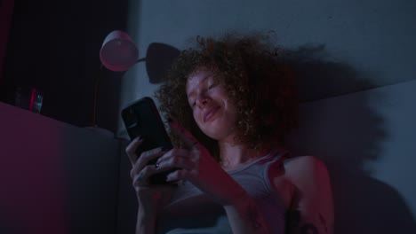 woman using phone in bedroom at night