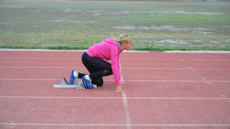 female athlete taking starting position on running track 4k