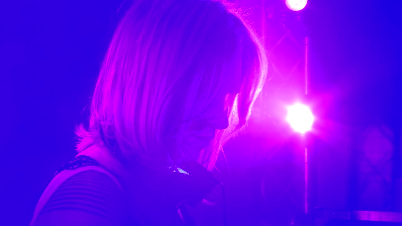 DJ donna che mixa musica sotto luci di scena blu e viola vibranti