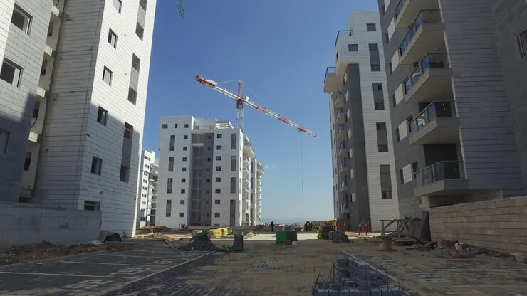 Cantiere edile con operai e gru, nuove case, ripresa in tilt-down.