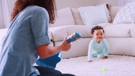 black toddler boy crawling to his mum playing ukulele