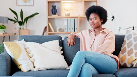 una mujer afro riendo relajándose en el sofá en casa
