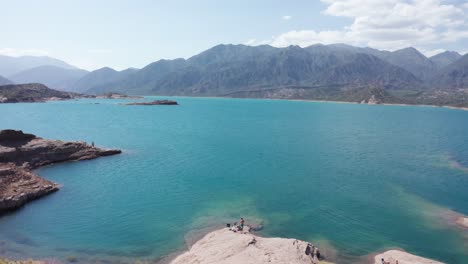 Man-standing-at-shore-of-blue-turquoise-water-lake-in-summer