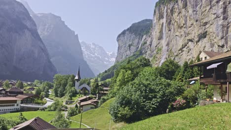 Hermosa-Vista-En-El-Pueblo-De-Los-Alpes-Con-Iglesia,-Cascada,-Montaña-Y-Colina-1