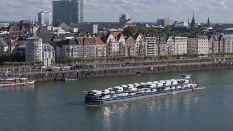 riverfront of dusseldorf city and cargo ship loaded with cars, transportation on the river