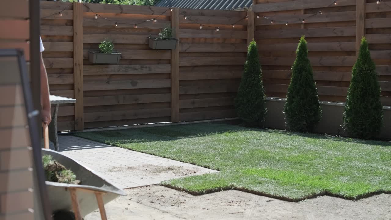 Man Laying Sod Grass in Backyard Garden for Lawn Installation and Landscaping Project, Focused on Home Improvement and Outdoor Maintenance for a Fresh, Green Lawn in a Residential Yard