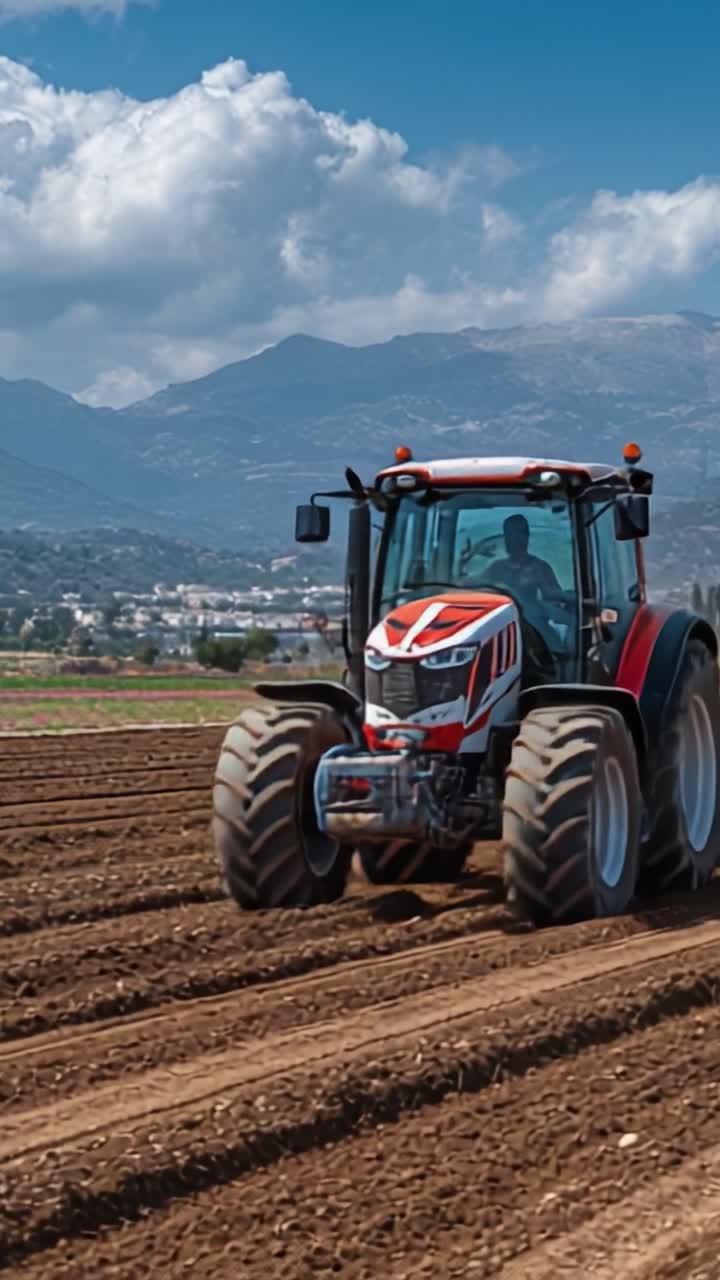 Un potente trattore che ara un terreno agricolo fertile sullo sfondo di maestose montagne e un cielo vibrante, mettendo in mostra la prodezza agricola e la produttività rurale.