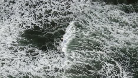 el dron se aleja de un surfista solitario para revelar grandes olas texturizadas