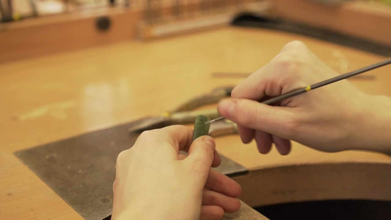 Closeup shot of filling a small hole in green stone from New Zealand in jewelry factory