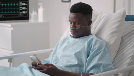 a black man is lying on a hospital bed and plowing a message to his friends and relatives from the hospital. communication with loved ones in the hospital via the internet and mobile devices