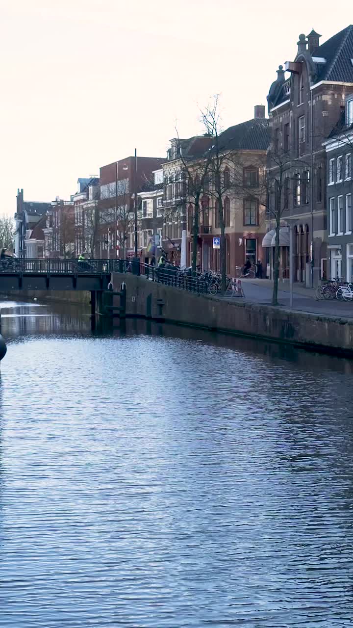 Persone che passeggiano e vanno in bicicletta lungo un canale storico cittadino