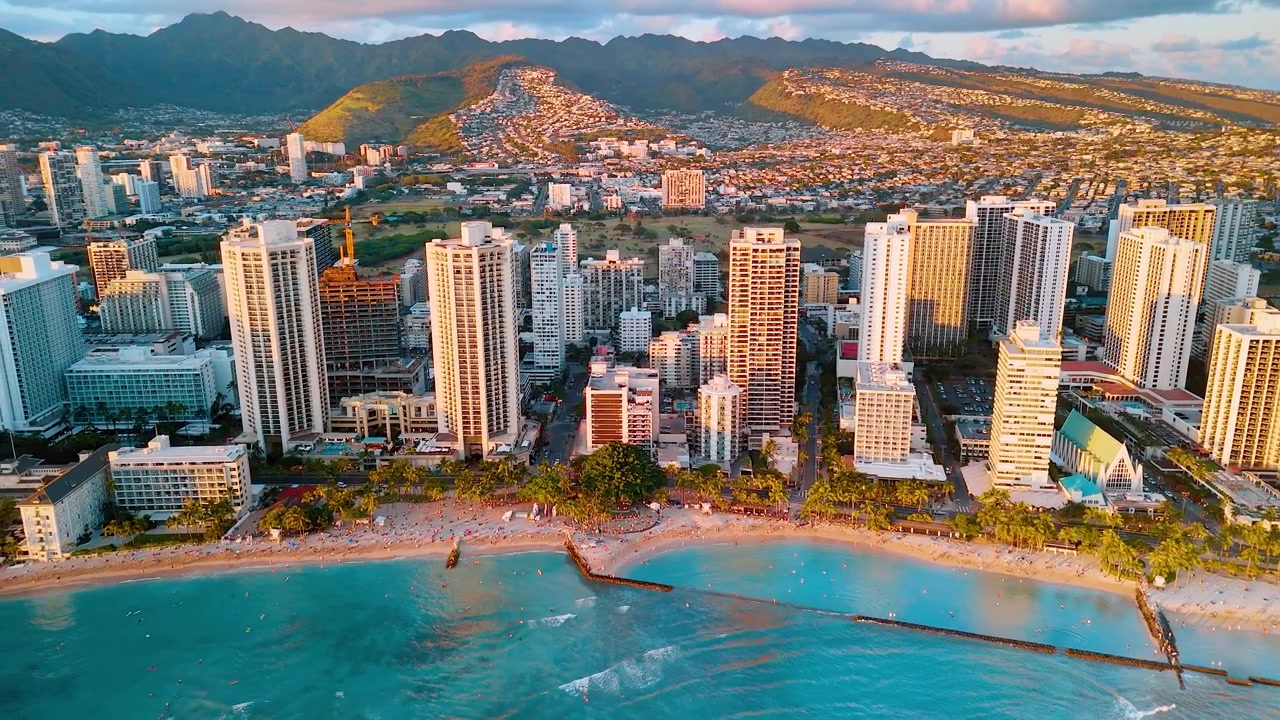 Luce del tramonto sulle torri grattacielo di Waikiki, Honolulu, Hawaii. L'ora d'oro illumina grattacieli e il quartiere collinare vicino alla montagna