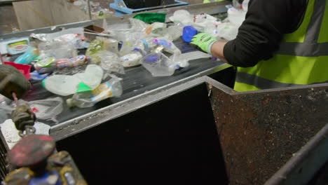 personas clasificando botellas de plástico y latas de aluminio en una cinta transportadora en una planta de reciclaje
