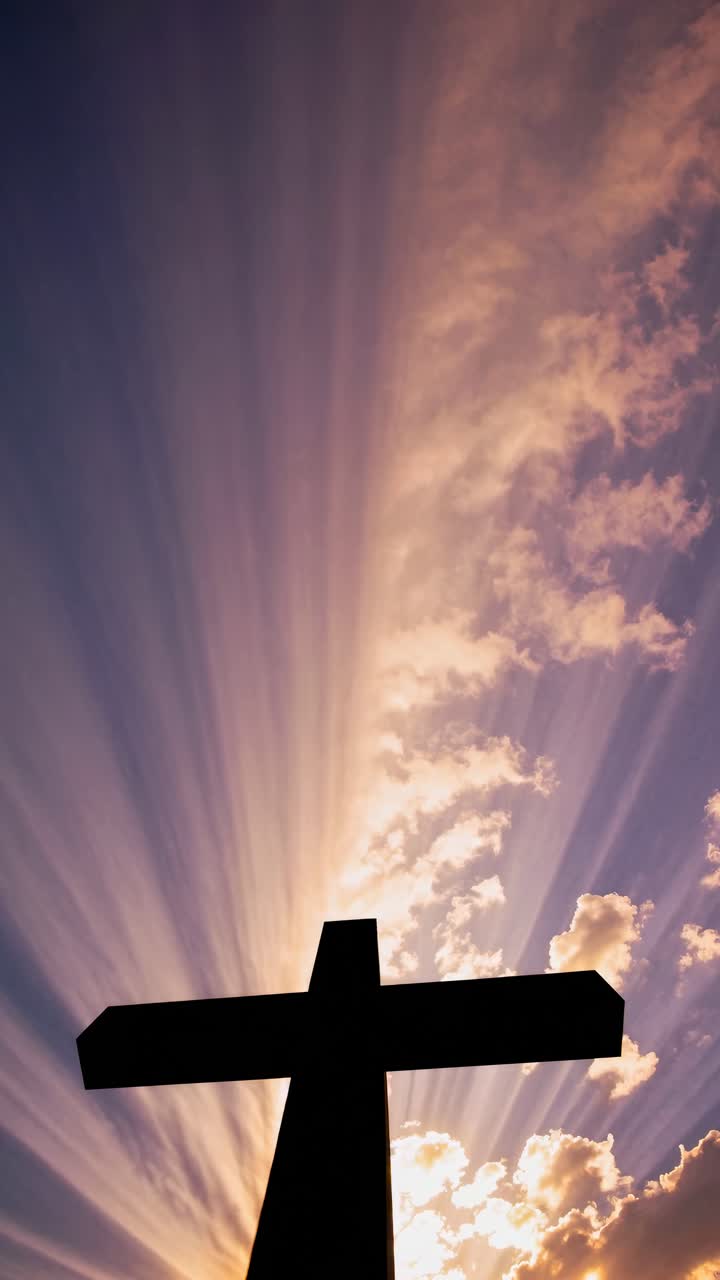 Silhouette of a cross against a dramatic sunset sky, captured from a low angle