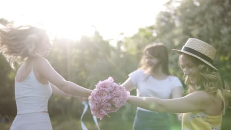 three happy, smiling girls dancing in the circle. sunlit meadow. happy time together