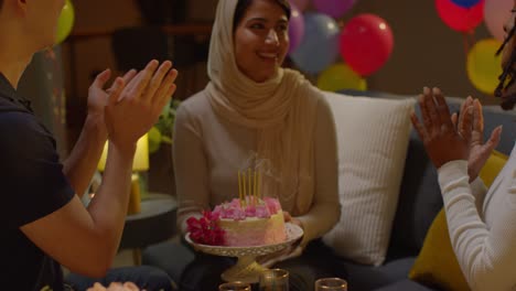 amigos multiculturales dando a la mujer pastel de cumpleaños con velas en una fiesta en casa 1