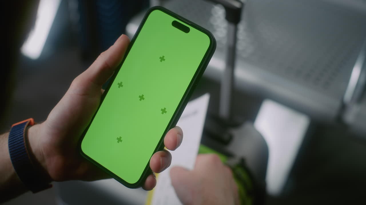 Person holding a smartphone and boarding pass at the airport.