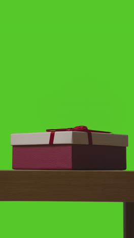 vertical video of present in gift wrapped box on table shot against green screen