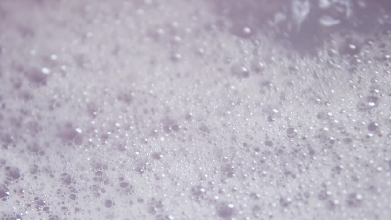 Close up shot of foam and soapy bubbles on a moving water surface, self care, bathtub, background