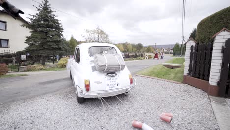 wedding white old car with cans leaving the home road