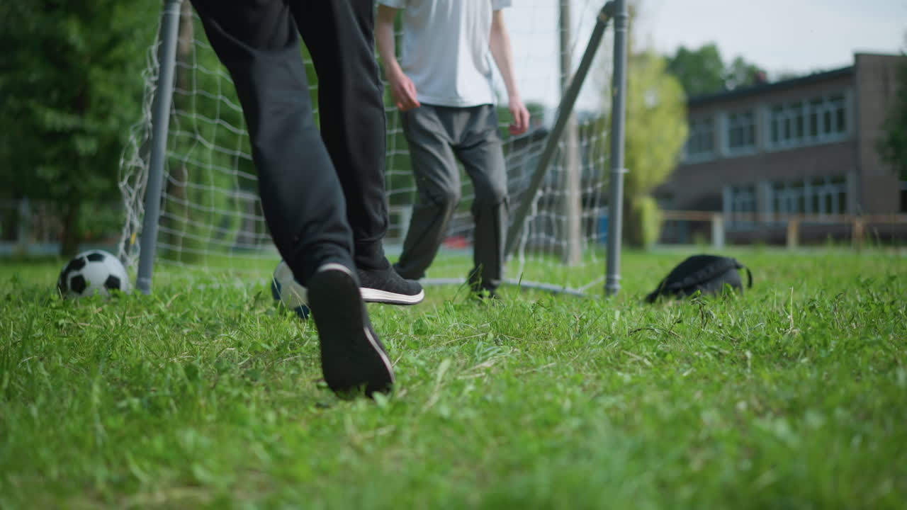 A close-up of a soccer ball is kicked into the goal post, as the goalkeeper jumps and rests on the ball from behind
