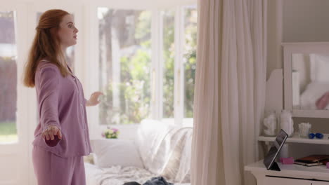 beautiful young woman practicing ballet dancing in bedroom rehearsing dance on weekend morning wearing pajamas