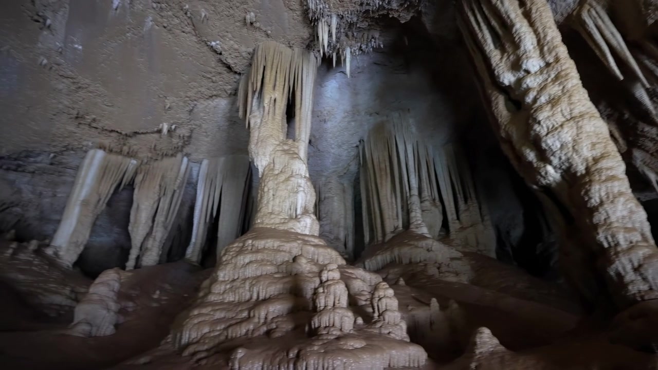 Dimly Lit Limestone Cave Chamber Showcasing Towering Stalagmites And Delicate Stalactites, Damp Calcite