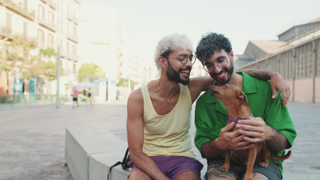 Feliz pareja gay sentada con su perro en una plaza de la ciudad