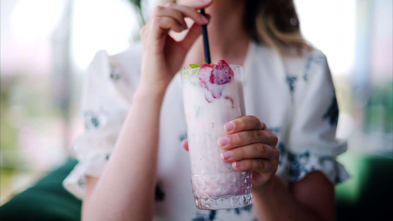 Woman drinking a strawberry drink with a black straw at a restaurant
