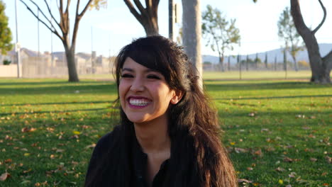 A-pretty-girl-smiling-and-laughing-with-a-digital-camera-practicing-her-photography-by-taking-photos-of-colorful-fall-and-autumn-leaves