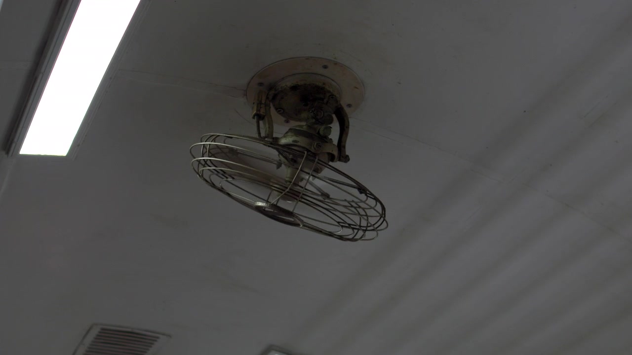 Vintage Metal Caged Ceiling Fan Rotating Beneath White Interior Roof