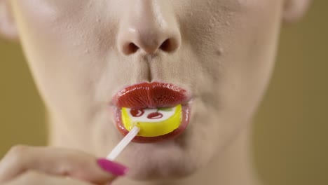 cara de primer plano, linda mujer caucásica lamia una piruleta de cereza amarilla