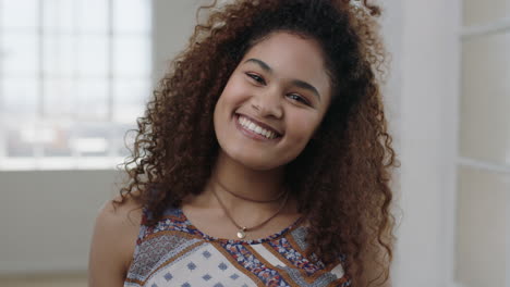 Lindo-Retrato-De-Mujer-Joven-De-Una-Chica-Bastante-Mestiza-Sonriendo-Posando-Para-La-Cámara-Alegre-Cabello-Rizado-Femenino-Positivo-En-El-Fondo-Del-Apartamento