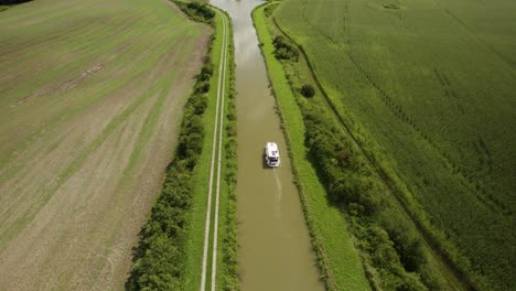 Toma-Aérea-De-Una-Pequeña-Embarcación-En-El-Canal-En-Medio-De-Los-Campos-Agrícolas