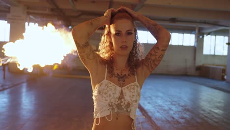 Tattooed woman with fire explosion in dramatic movie scene. she walks and is unimpressed has no afraid