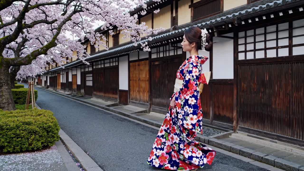Un video cattura una donna in kimono floreale che cammina lungo una tradizionale strada giapponese