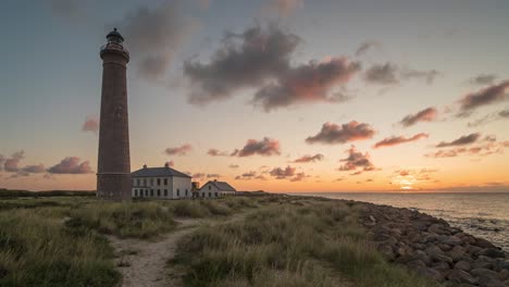faro gris de skagen con el sol saliendo en el horizonte durante el amanecer
