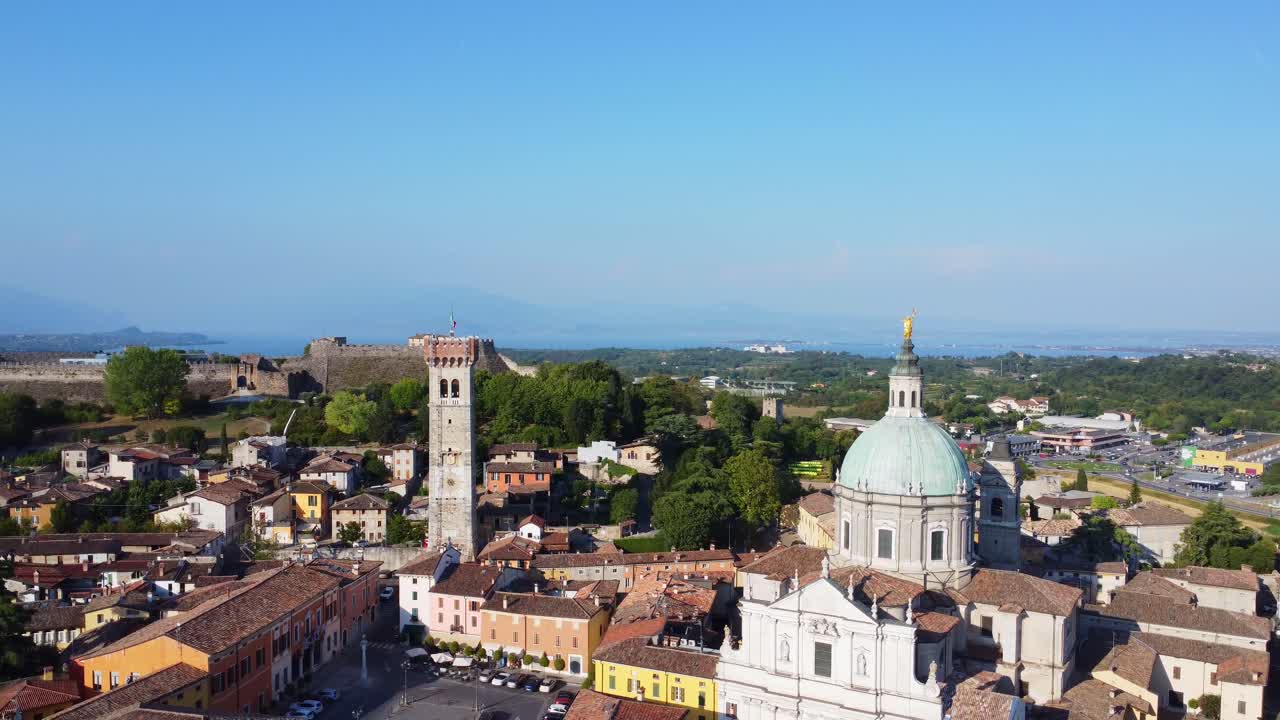 Drone view over Lonato del Garda featuring the majestic Basilica of San Giovanni and the Rocca fortress, with Lake Garda shimmering in the background.