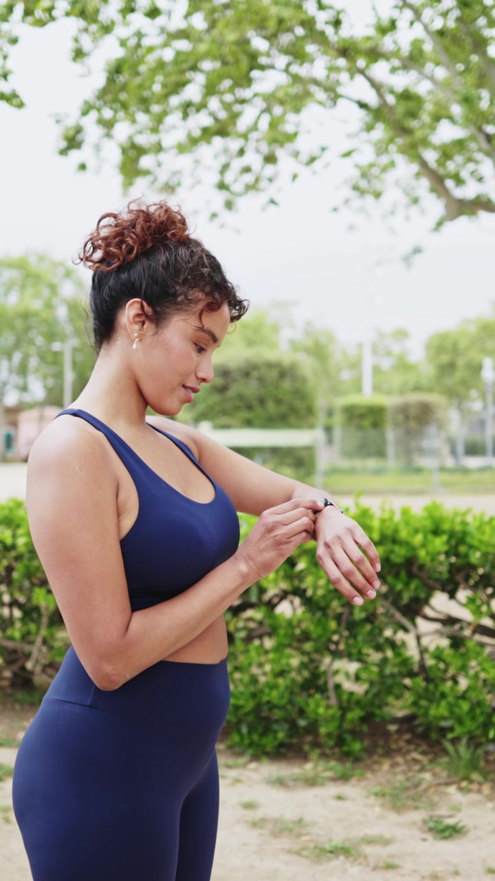 Young Woman Checking Smartwatch Before Starting Her Run in the Park