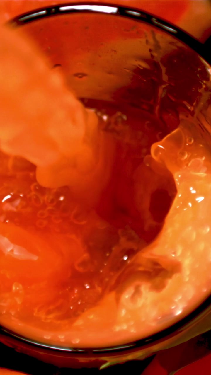Primo piano al rallentatore di succo d'arancia vivace che si versa in un bicchiere