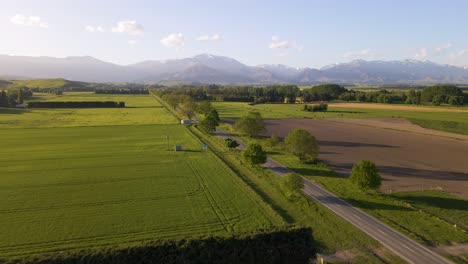 Fast-aerial-tracking-shot-of-car-traveling-towards-a-beautiful-mountain-range-at-sunset