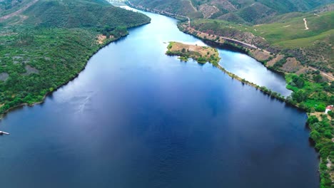 aerial-shot-of-deep-blue-river-flowing-through-steep-valley,-4k