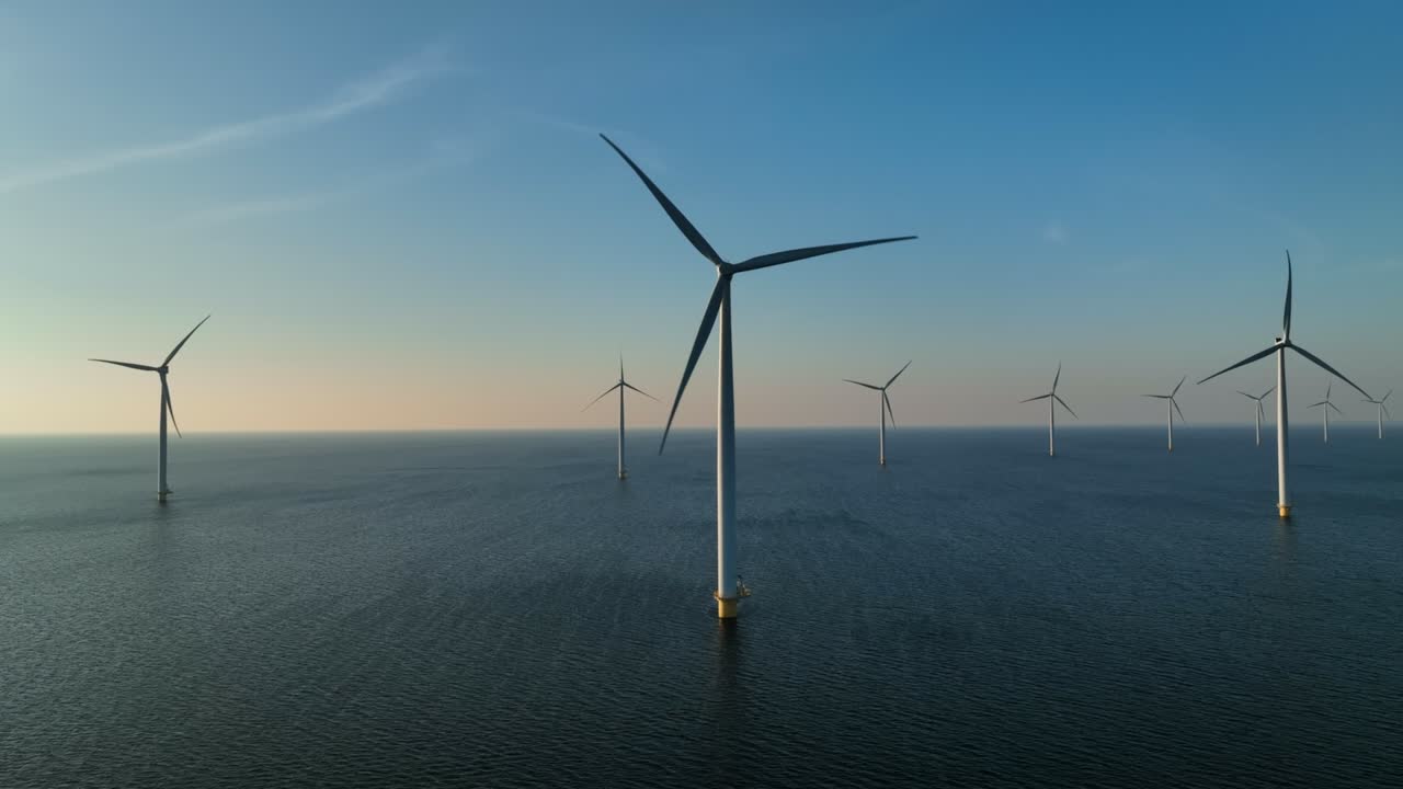 태양이 지는 동안 해상 풍력 공원에서 지속 가능한 재생 가능한 에너지를 생산하는 풍력 터빈.